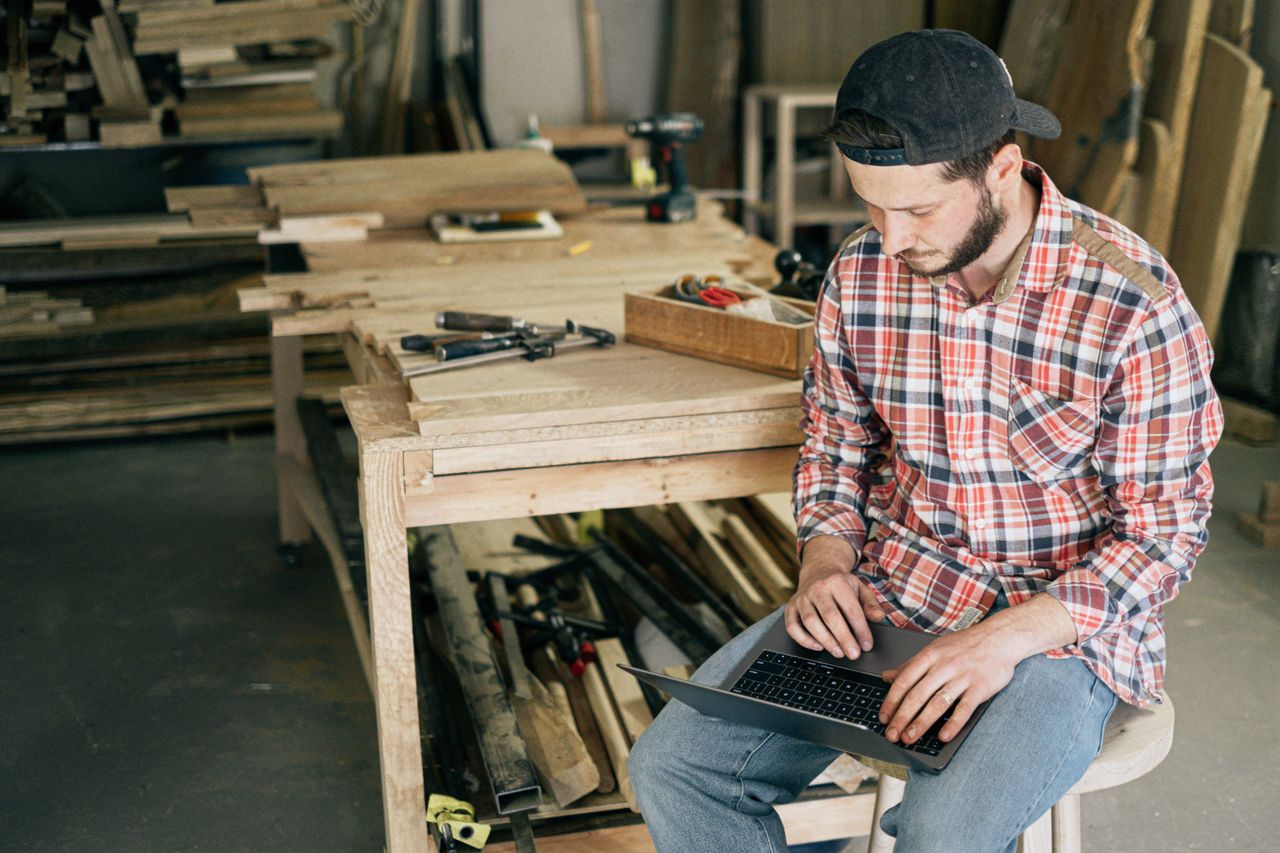 A small-business owner working on a laptop in their workshop