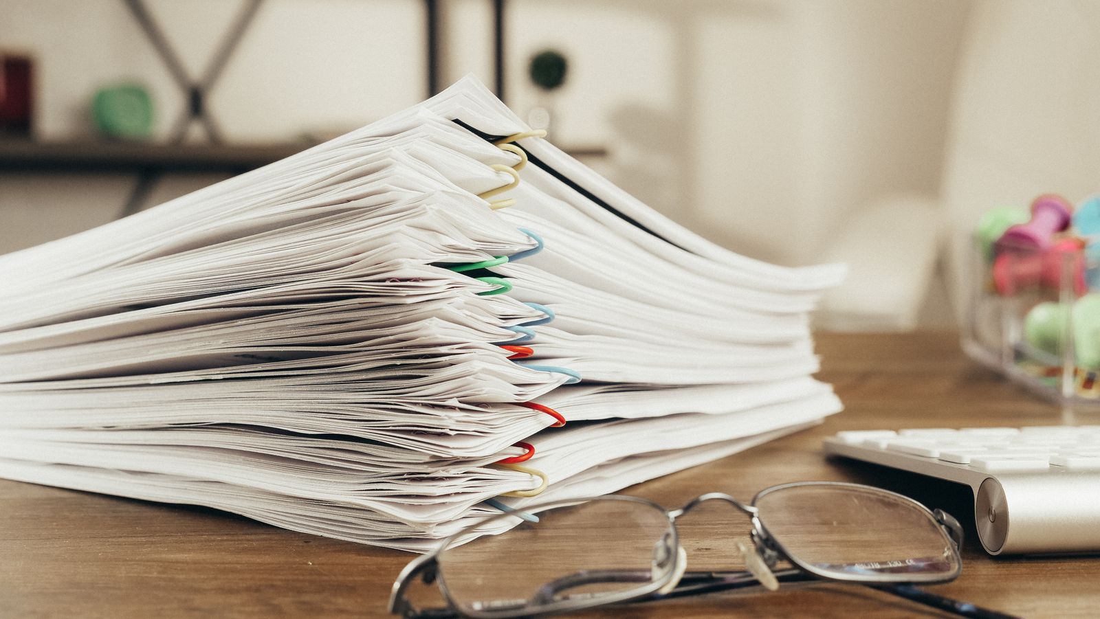 A tall stack of paperwork on a desk